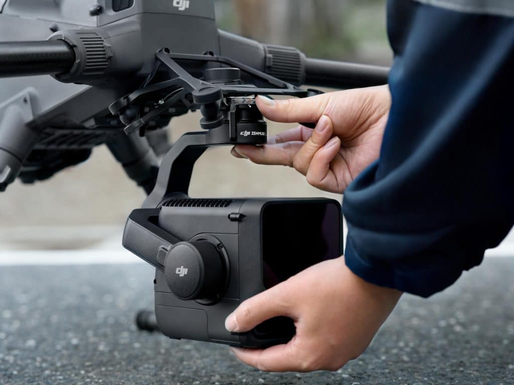 Gros plan d'une personne attachant un module DJI L3 LiDAR à un drone en plein air, en se concentrant sur les mains qui connectent l'appareil. Le drone et le module portent la marque DJI.