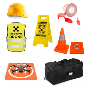 Divers équipements de sécurité destinés à l'utilisation de drones, notamment un casque de chantier jaune, un gilet de sécurité, un panneau d'avertissement, du ruban adhésif rouge, un cône et un tapis de sécurité orange, un tapis d'atterrissage, un drone et un sac de voyage noir, disposés avec soin sur un fond blanc.