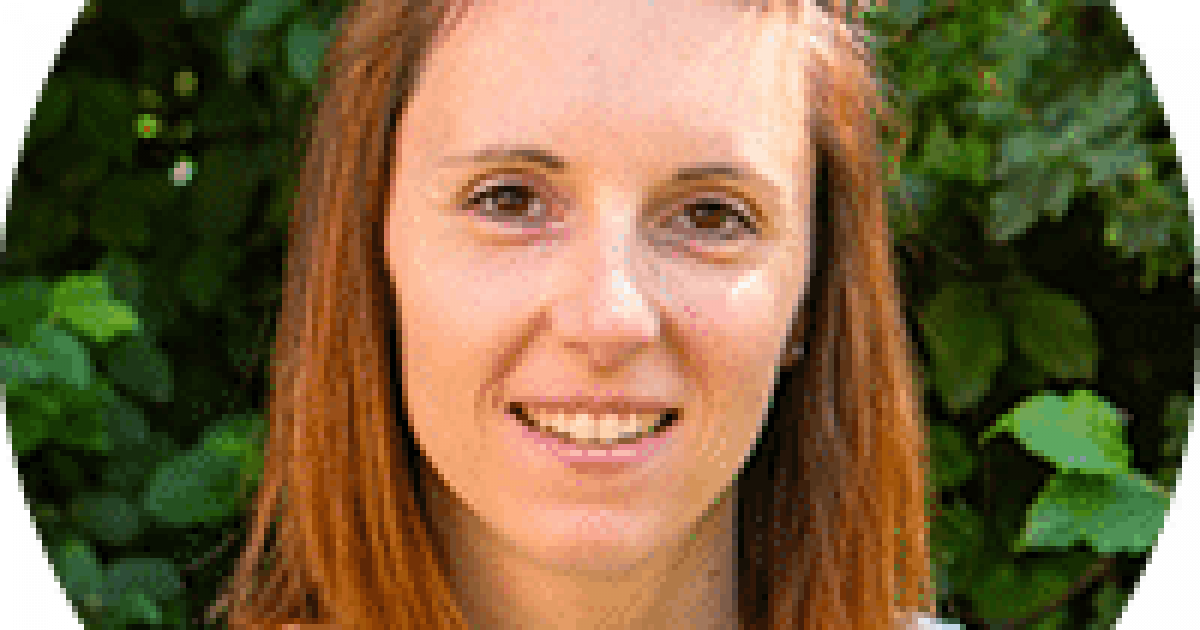 Une femme aux cheveux roux qui sourit.