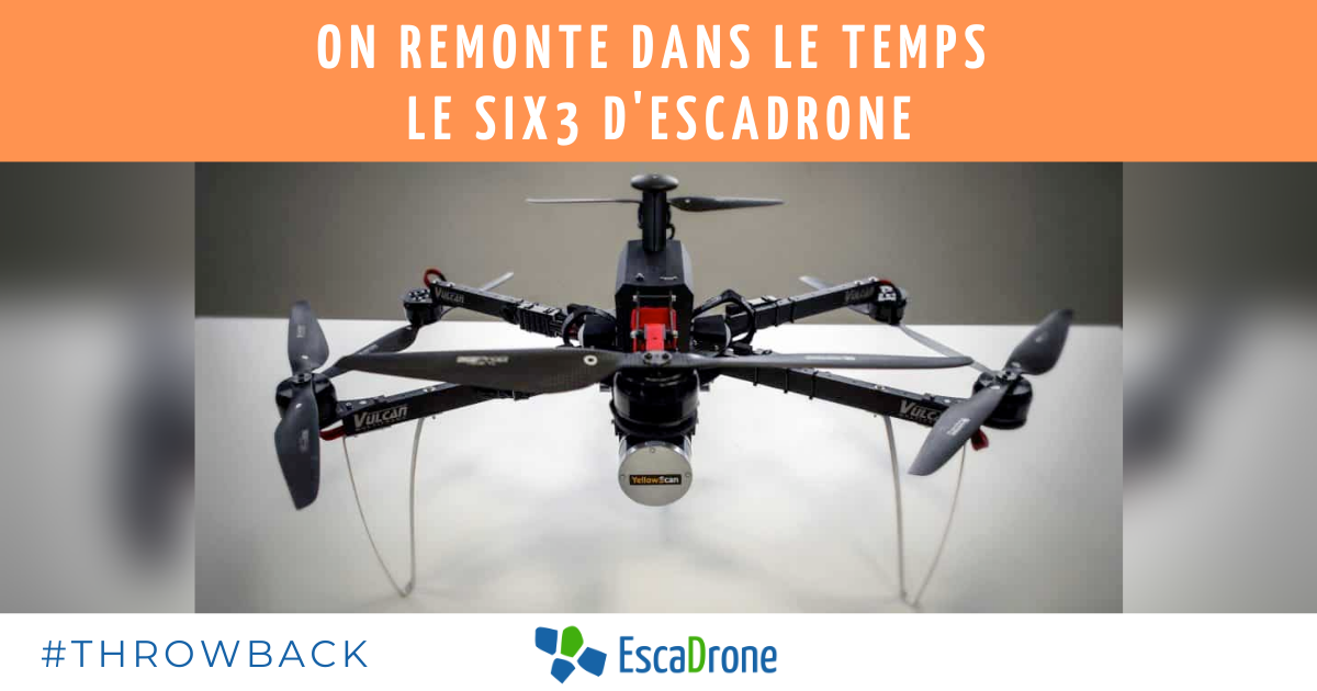 Un drone quadcopter Six3 noir étiqueté Vulcan est présenté sur une surface grise et blanche. Le texte en français au-dessus se lit comme suit : "On remonte dans le temps, le Six3 d'Escadrone : On remonte dans le temps, le Six3 d'Escadrone. #THROWBACK et le logo EscaDrone sont affichés en dessous.