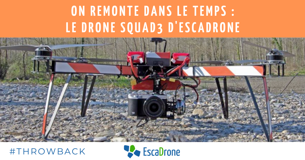 Un grand drone professionnel Squad3 avec une caméra montée est positionné sur un sol rocheux en plein air. Des bandes d'avertissement orange et blanches sont apposées sur ses bras. Un texte en français et le logo EscaDrones apparaissent au-dessus et en dessous du drone.